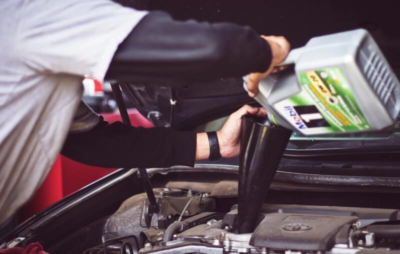 Mann wechselt Öl bei Auto